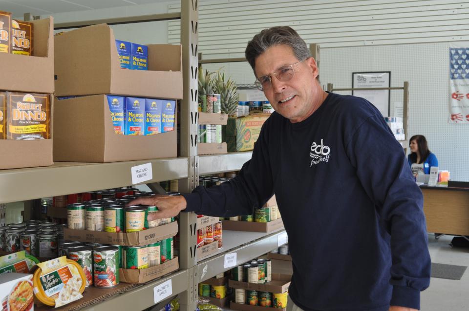Middle aged man standing by shelves of canned food